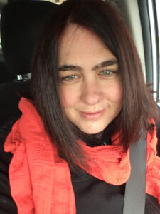 Photo de Nathalie, elle a les cheveux bruns et porte un foulard orange.